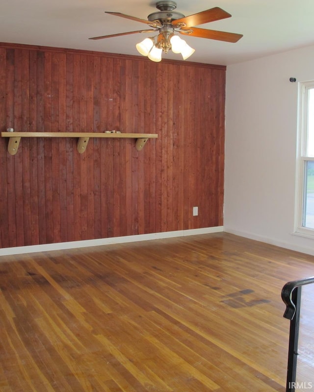 2325 Balmoral Blvd, Kokomo, IN 46902 - unfurnished living room featuring wood finished floors, ceiling fan, baseboards, and wooden walls