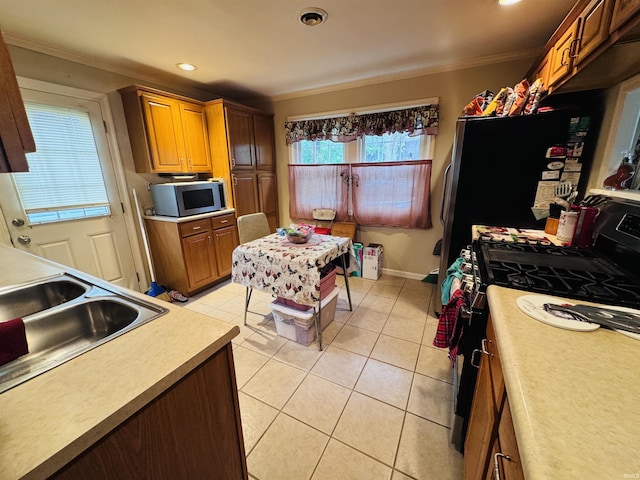 1005 Elm St, Plymouth, IN 46563 - kitchen with stainless steel microwave, range with gas stovetop, crown molding, light tile patterned floors, and a sink