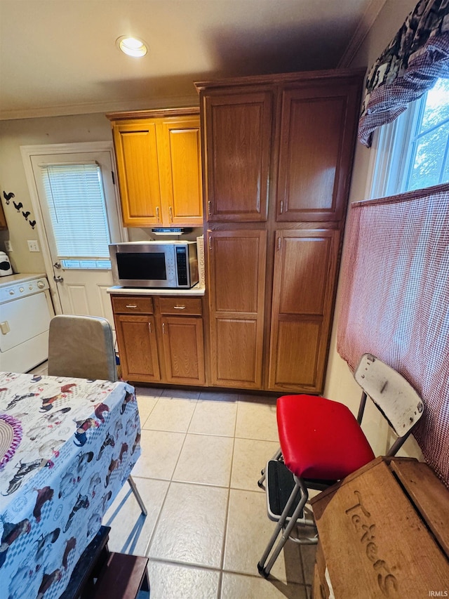 1005 Elm St, Plymouth, IN 46563 - kitchen featuring stainless steel microwave, washer / dryer, ornamental molding, light tile patterned floors, and brown cabinetry