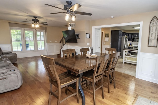 917 E Mill Creek Rd, Greensburg, IN 47240 - dining area featuring a decorative wall, a wainscoted wall, light wood-style flooring, a ceiling fan, and stairs