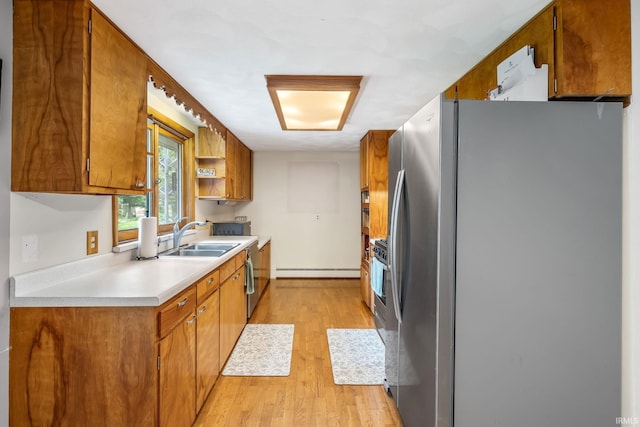 907 N Orchard Dr, North Manchester, IN 46962 - kitchen with freestanding refrigerator, a sink, baseboard heating, brown cabinetry, and light wood-style flooring