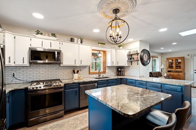 3705 E Forest Glen Ave, Leesburg, IN 46538 - kitchen with appliances with stainless steel finishes, a sink, blue cabinetry, a peninsula, and decorative backsplash