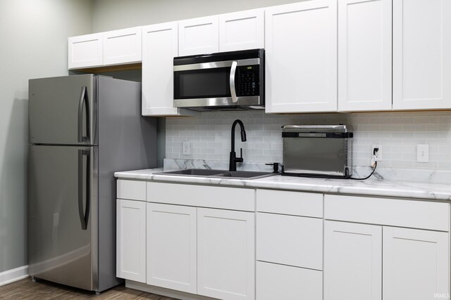 1154 S Deer Run, Ellettsville, IN 47429 - kitchen with stainless steel appliances, a sink, white cabinets, backsplash, and wood finished floors