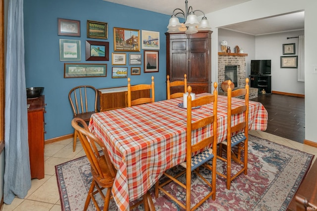 4641 W Harvest Ln, Bloomington, IN 47404 - dining room with light tile patterned floors, baseboards, a fireplace, and a chandelier