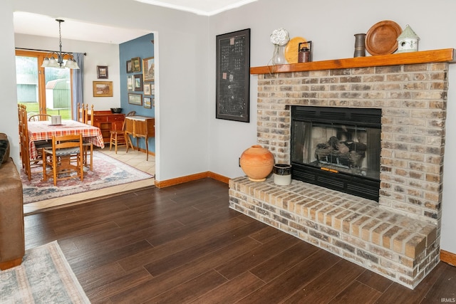4641 W Harvest Ln, Bloomington, IN 47404 - living room featuring baseboards, wood finished floors, a fireplace, and a chandelier