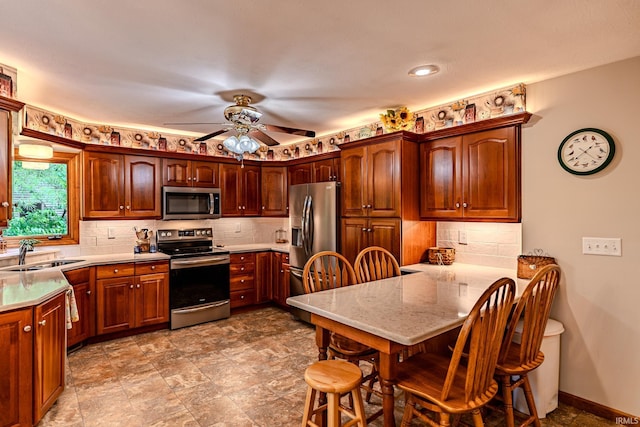 70 Mayflower Ct, Lafayette, IN 47909 - kitchen with stainless steel appliances, a sink, a peninsula, a ceiling fan, and tasteful backsplash