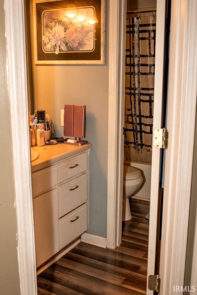 2447 S Meridian St, Marion, IN 46953 - full bath featuring wood finished floors, toilet, vanity, curtained shower, and baseboards