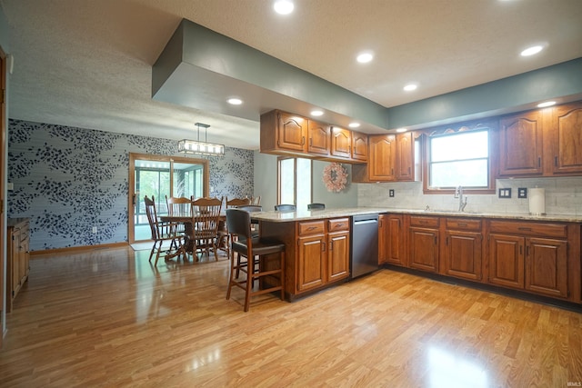 4630 E Armstrong Rd, Leesburg, IN 46538 - kitchen with wallpapered walls, a peninsula, brown cabinets, a sink, and light wood-style floors