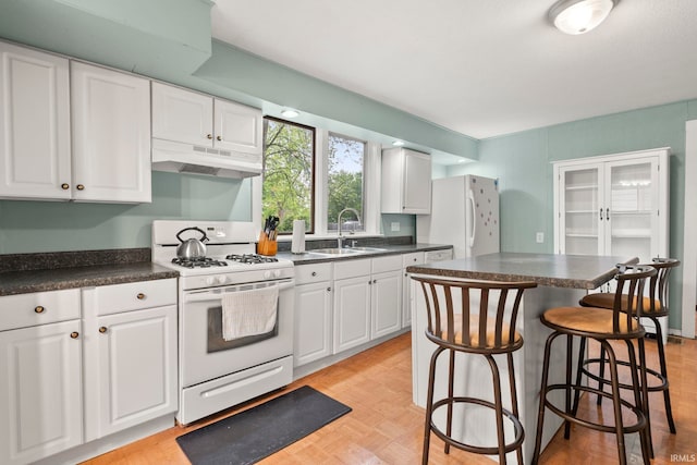 726 S Johnson, Bluffton, IN 46714 - kitchen featuring under cabinet range hood, a sink, white appliances, dark countertops, and white cabinetry