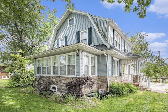 1224 N Main St, Elkhart, IN 46514 - view of side of home featuring a gambrel roof, a lawn, and stone siding