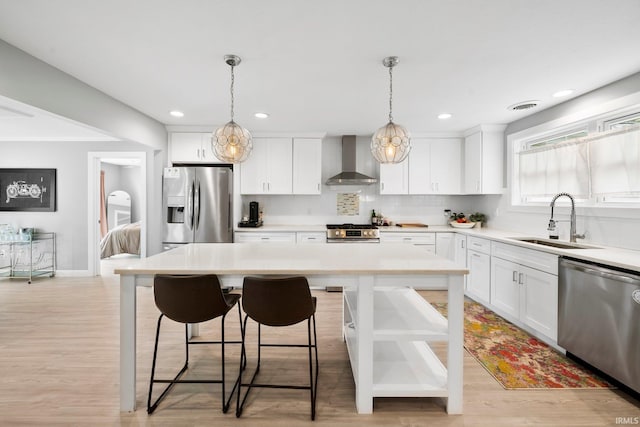1718 Churchill Dr, South Bend, IN 46617 - kitchen with stainless steel appliances, wall chimney range hood, a sink, white cabinetry, and recessed lighting