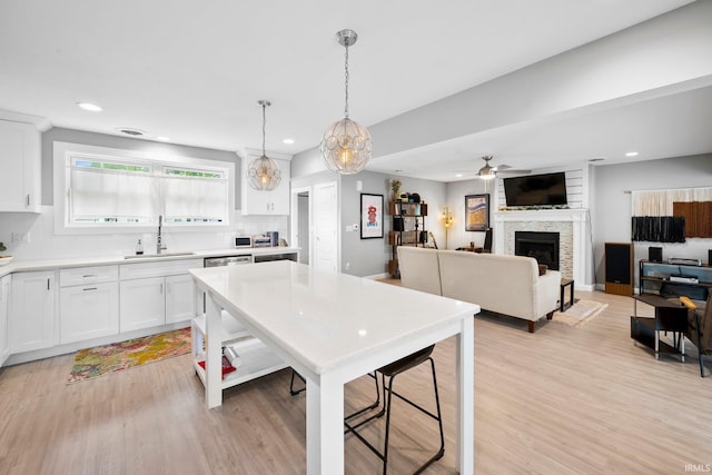 1718 Churchill Dr, South Bend, IN 46617 - kitchen featuring a sink, a large fireplace, light countertops, white cabinets, and light wood-style floors