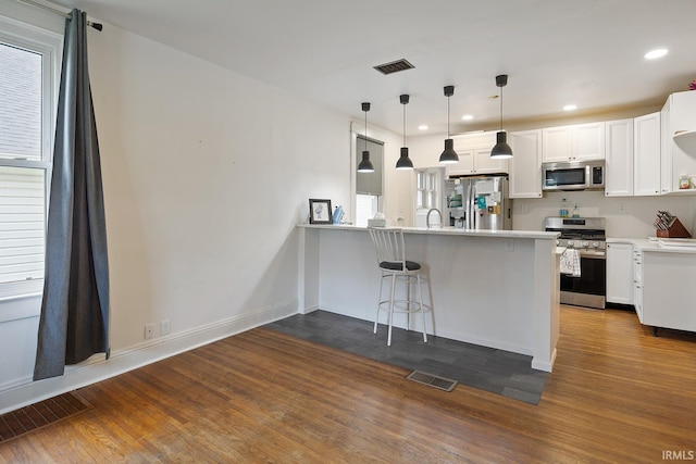 1413 Franklin St, Lafayette, IN 47905 - kitchen with appliances with stainless steel finishes, a peninsula, dark wood-type flooring, white cabinets, and recessed lighting