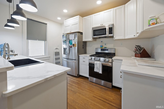1413 Franklin St, Lafayette, IN 47905 - kitchen featuring appliances with stainless steel finishes, a sink, wood finished floors, white cabinetry, and pendant lighting