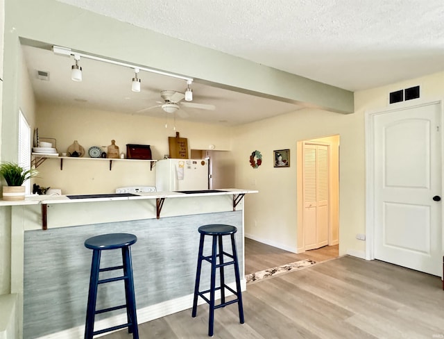 0731 S June Dr, Cromwell, IN 46732 - kitchen featuring freestanding refrigerator, a ceiling fan, wood finished floors, a kitchen breakfast bar, and a textured ceiling