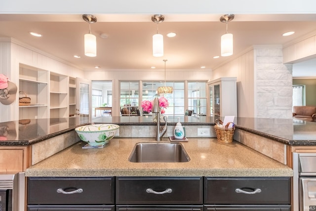4000 E Stonegate Dr, Bloomington, IN 47401 - kitchen with a sink, crown molding, dark stone counters, pendant lighting, and a center island with sink