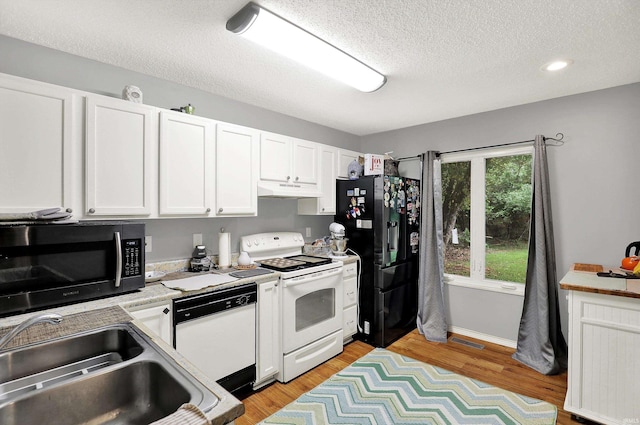2210 S Laurelwood Cir, Bloomington, IN 47401 - kitchen featuring white appliances, a sink, white cabinetry, a textured ceiling, and light wood-style floors