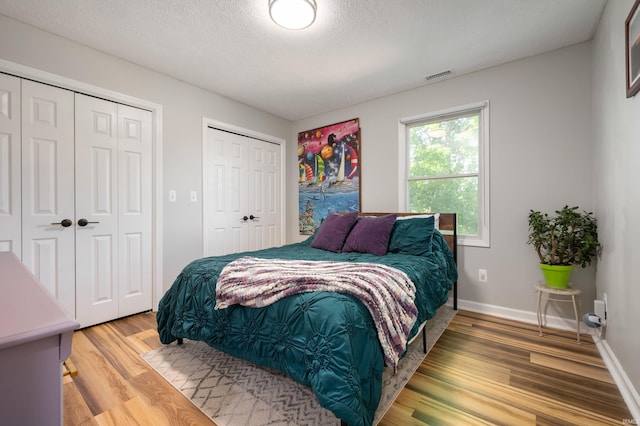 7805 W Kennedy Pkwy, Yorktown, IN 47396 - bedroom featuring multiple closets, light wood-style flooring, a textured ceiling, and baseboards