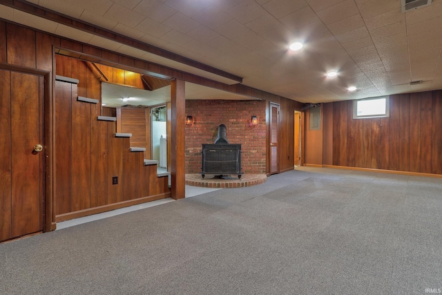 2305 E Virginia St, Evansville, IN 47711 - unfurnished living room with light carpet, wooden walls, a wood stove, stairs, and baseboards