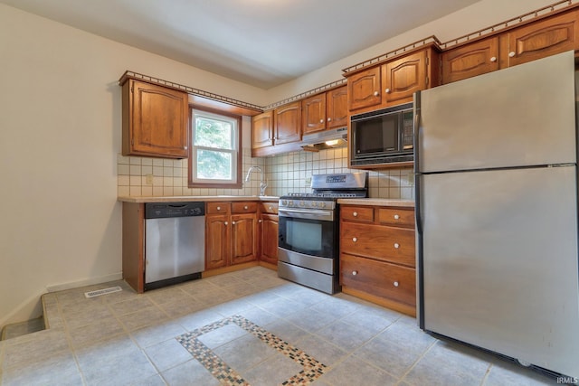 2305 E Virginia St, Evansville, IN 47711 - kitchen with appliances with stainless steel finishes, under cabinet range hood, light countertops, and brown cabinetry