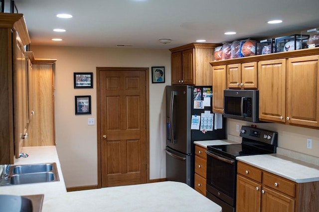 204 Coronet St, Angola, IN 46703 - kitchen featuring appliances with stainless steel finishes, light countertops, brown cabinets, recessed lighting, and a sink