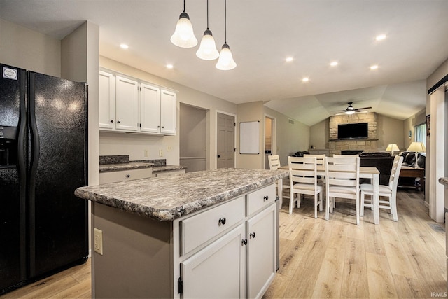 50576 W Park Ln, Granger, IN 46530 - kitchen with black refrigerator with ice dispenser, ceiling fan, light wood-style flooring, white cabinets, and a stone fireplace