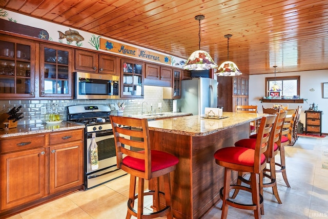8818 N 1132 W, Monticello, IN 47960 - kitchen featuring appliances with stainless steel finishes, a kitchen breakfast bar, tasteful backsplash, hanging light fixtures, and light tile patterned floors