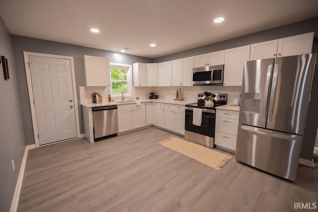 1034 Harter Blvd, Anderson, IN 46011 - kitchen with stainless steel appliances, decorative backsplash, light countertops, light wood-style flooring, and white cabinetry