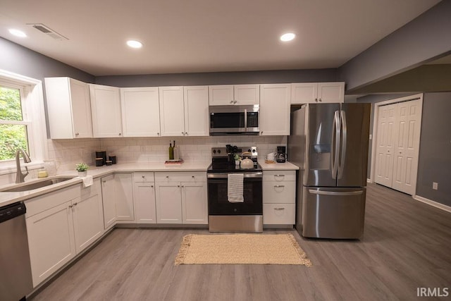 1034 Harter Blvd, Anderson, IN 46011 - kitchen featuring appliances with stainless steel finishes, a sink, light wood-style floors, backsplash, and light countertops