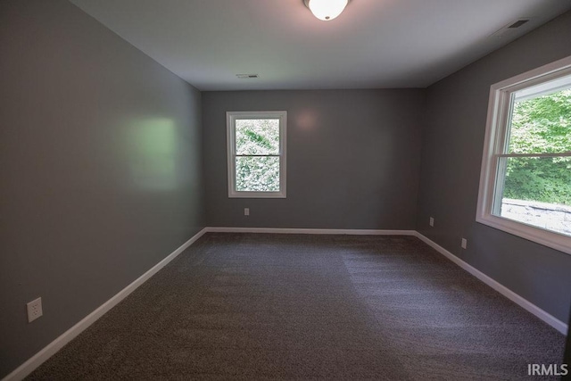 1034 Harter Blvd, Anderson, IN 46011 - empty room with healthy amount of natural light, dark colored carpet, and baseboards
