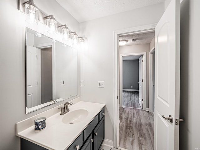 2747 Thornhill Dr, Evansville, IN 47725 - bathroom featuring a textured ceiling, vanity, wood finished floors, and baseboards