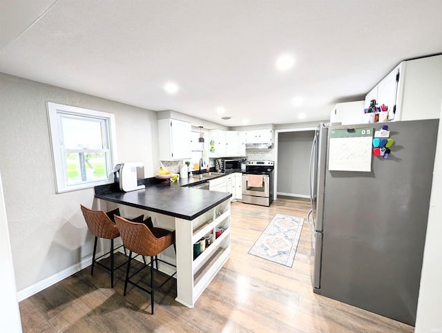 7382 Denise Dr, Fort Wayne, IN 46835 - kitchen with appliances with stainless steel finishes, a peninsula, a sink, dark countertops, and under cabinet range hood