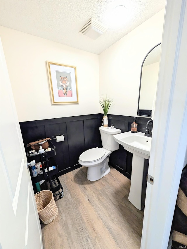 7382 Denise Dr, Fort Wayne, IN 46835 - half bath featuring wood finished floors, a wainscoted wall, toilet, a textured ceiling, and a sink