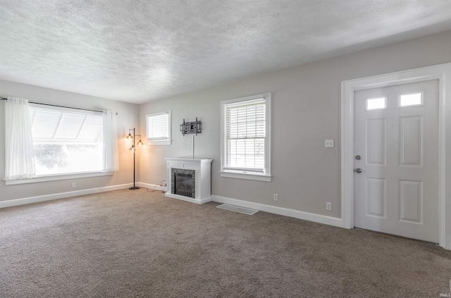 2500 N Govenor St, Evansville, IN 47711 - unfurnished living room featuring a textured ceiling, baseboards, carpet flooring, and a glass covered fireplace