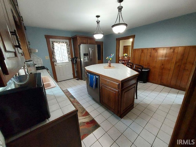 306 E 8th St, Jasper, IN 47546 - kitchen featuring tile countertops, stainless steel appliances, wood walls, light tile patterned flooring, and a wainscoted wall
