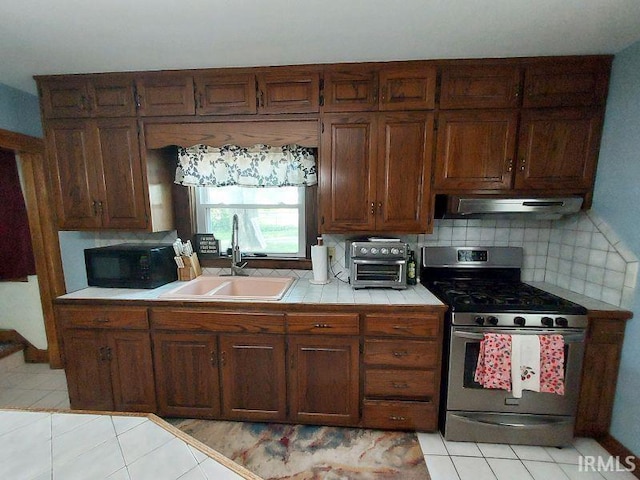 306 E 8th St, Jasper, IN 47546 - kitchen featuring stainless steel gas range, tile countertops, a sink, black microwave, and under cabinet range hood