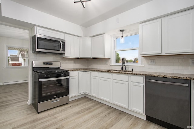 718 W 8th St, Mishawaka, IN 46544 - kitchen with stainless steel appliances, a sink, light wood-style floors, and dark stone countertops
