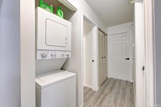 3220 E John Hinkle Pl Unit F, Bloomington, IN 47408 - laundry room featuring stacked washing machine and dryer, light wood-type flooring, baseboards, and a textured ceiling