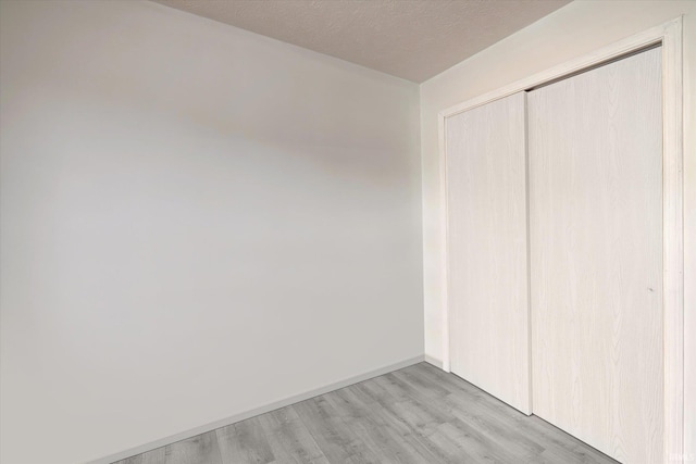 3220 E John Hinkle Pl Unit F, Bloomington, IN 47408 - unfurnished bedroom featuring light wood finished floors, a closet, and baseboards