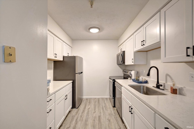 3220 E John Hinkle Pl Unit F, Bloomington, IN 47408 - kitchen with a sink, stainless steel appliances, light wood finished floors, and white cabinetry