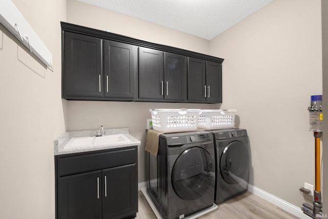 13909 Stone Table Blvd, Fort Wayne, IN 46845 - laundry area featuring cabinet space, light wood-style flooring, washer and dryer, baseboards, and a textured ceiling