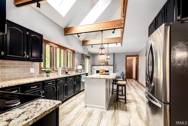 7819 Greenwell Rd, Churubusco, IN 46723 - kitchen with appliances with stainless steel finishes, dark cabinets, a breakfast bar area, decorative backsplash, and a center island