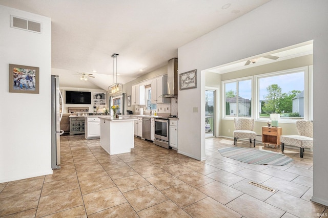 51405 Amesburry Way, Granger, IN 46530 - kitchen featuring a ceiling fan, wall chimney exhaust hood, appliances with stainless steel finishes, a kitchen island, and white cabinets