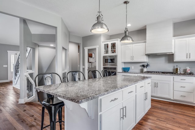 13606 Paperbark Trl, Fort Wayne, IN 46814 - kitchen featuring appliances with stainless steel finishes, a breakfast bar, dark wood-type flooring, light stone countertops, and white cabinets
