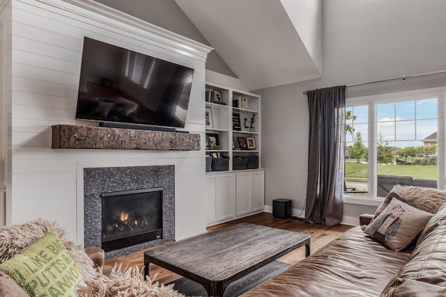 13606 Paperbark Trl, Fort Wayne, IN 46814 - living area with wood finished floors, a glass covered fireplace, vaulted ceiling, and baseboards