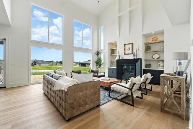 17807 Milazzo Cv, Huntertown, IN 46748 - living room with high vaulted ceiling, light wood-style floors, built in shelves, and a glass covered fireplace