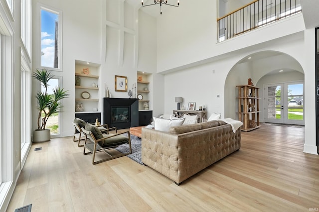 17807 Milazzo Cv, Huntertown, IN 46748 - living room with arched walkways, built in shelves, a high ceiling, light wood-style floors, and french doors