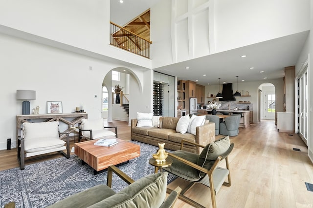 17807 Milazzo Cv, Huntertown, IN 46748 - living area featuring arched walkways, a towering ceiling, light wood-style flooring, and plenty of natural light