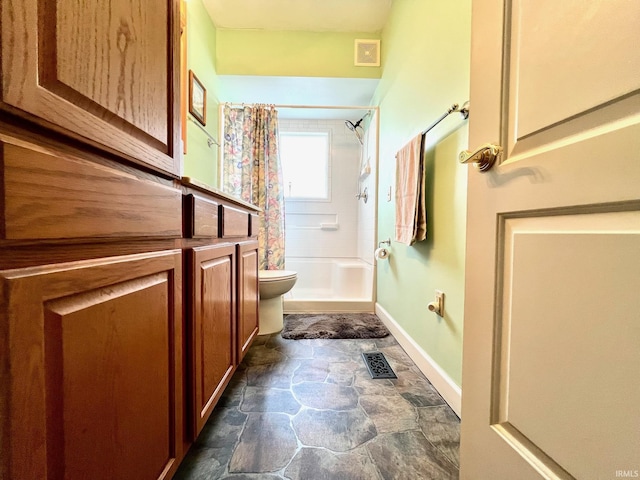 1405 19th St, Bedford, IN 47421 - bathroom with stone finish floors, toilet, shower / tub combo with curtain, and baseboards