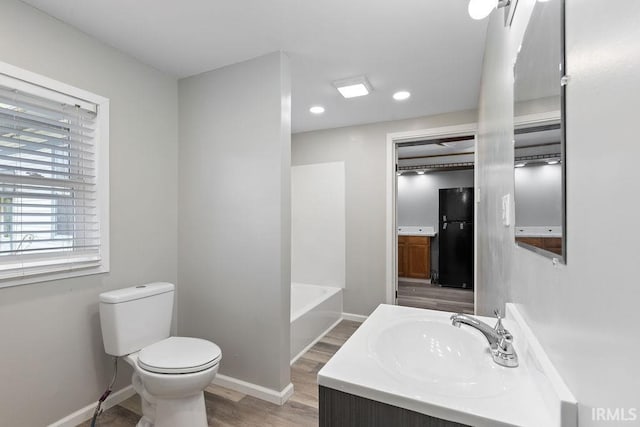 721 E Markland Ave, Kokomo, IN 46902 - bathroom featuring wood finished floors, toilet, a bath, baseboards, and recessed lighting